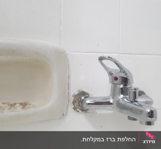 ברז כרום מותקן על קיר אריחים לבנים